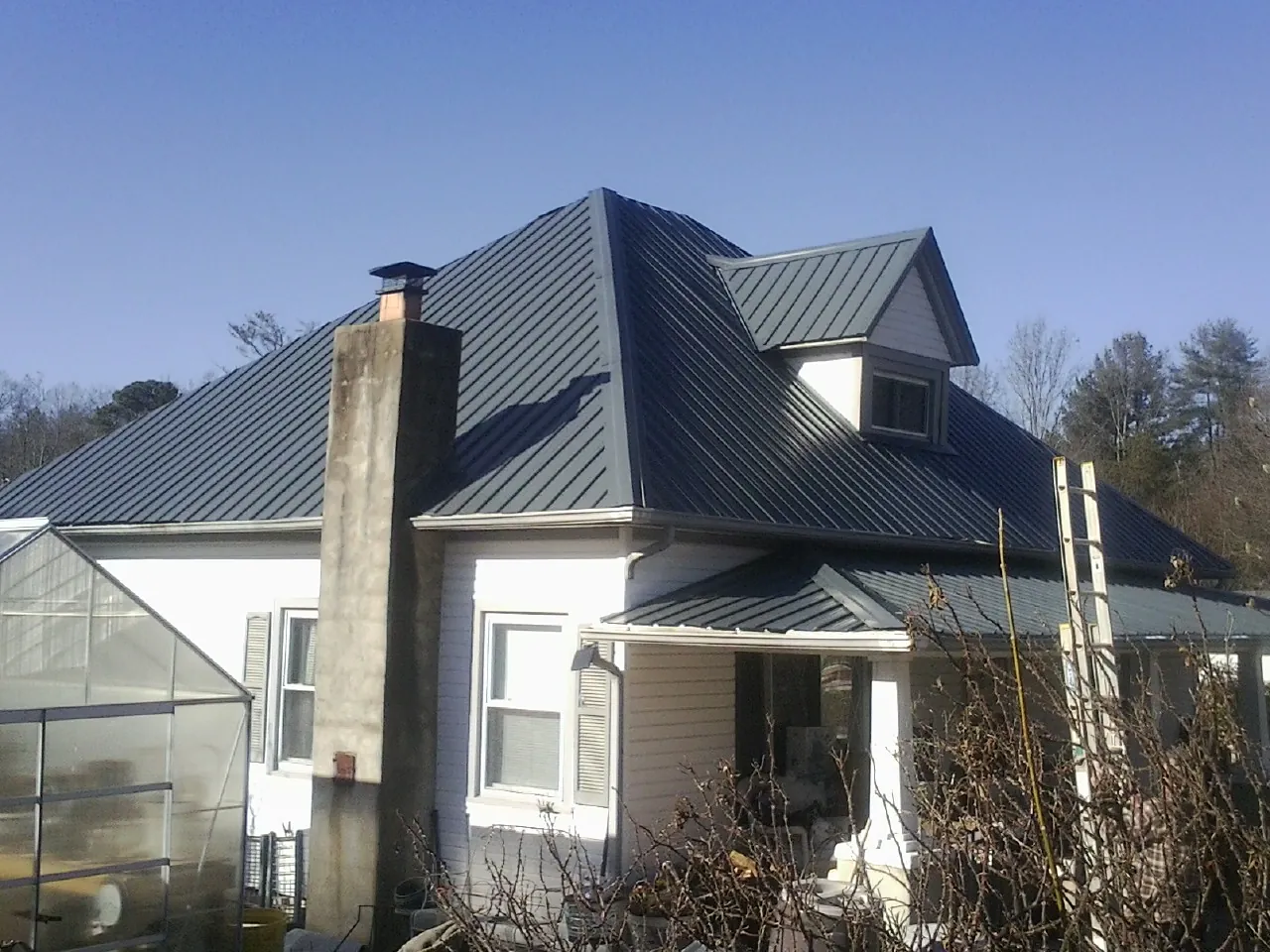 Dark blue standing seam metal roof on a white farmhouse with dormer — Slate & Tile Roof Repair by Roofing Brothers in South Gate