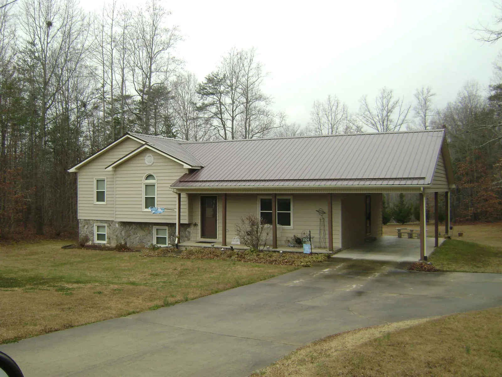 Brown metal roof on a tan split level home with an attached carport in South Gate