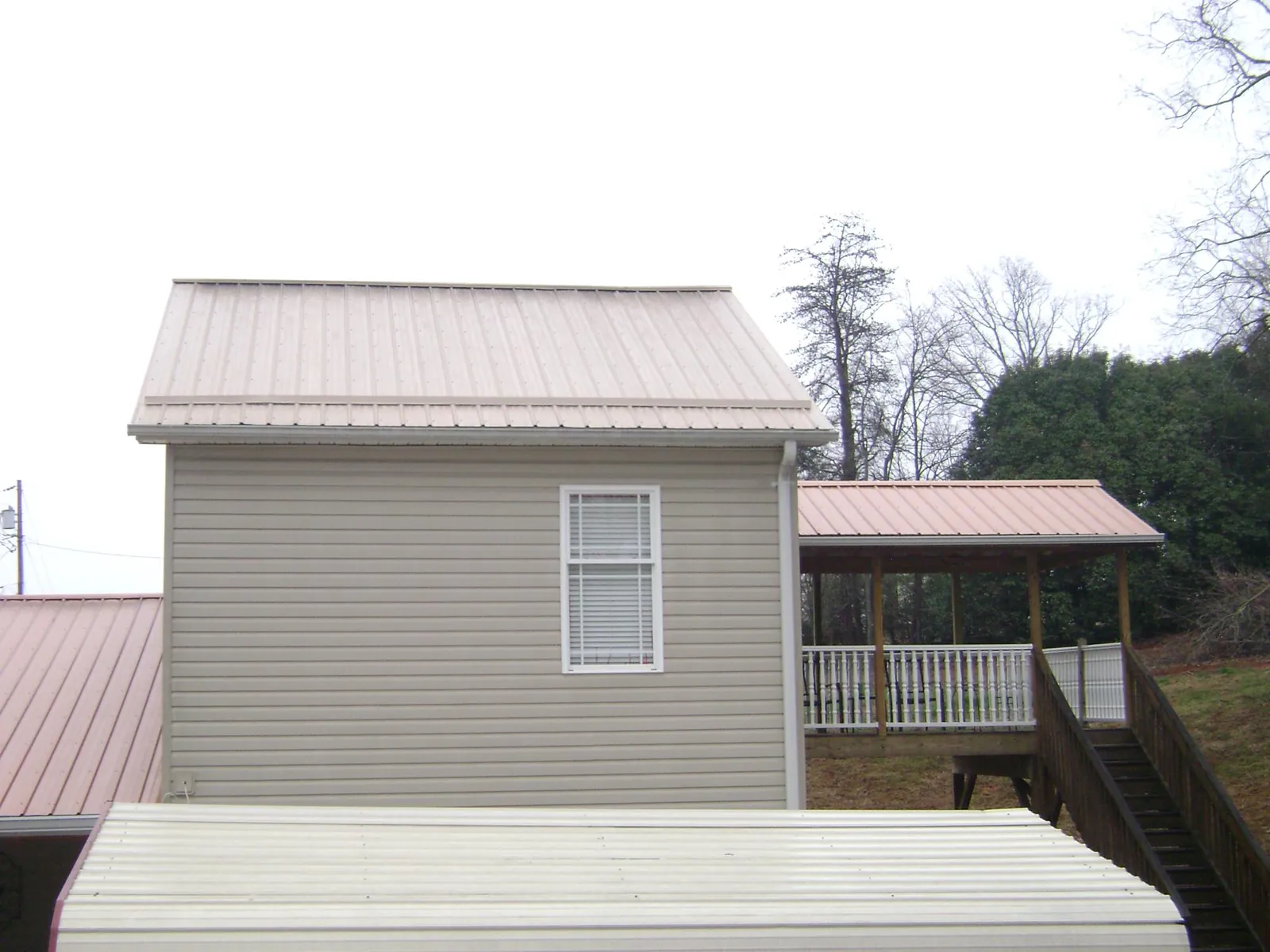 Tan metal roofs on a two story addition and attached porch, from a Roof Replacement job in South Gate