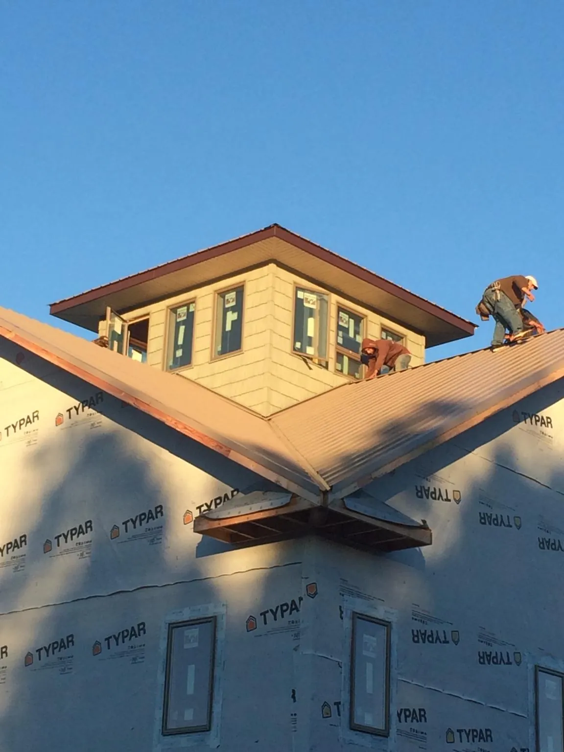 Roofers working around a rooftop cupola on a new metal roof at sunset — Roof Waterproofing in South Gate by Roofing Brothers